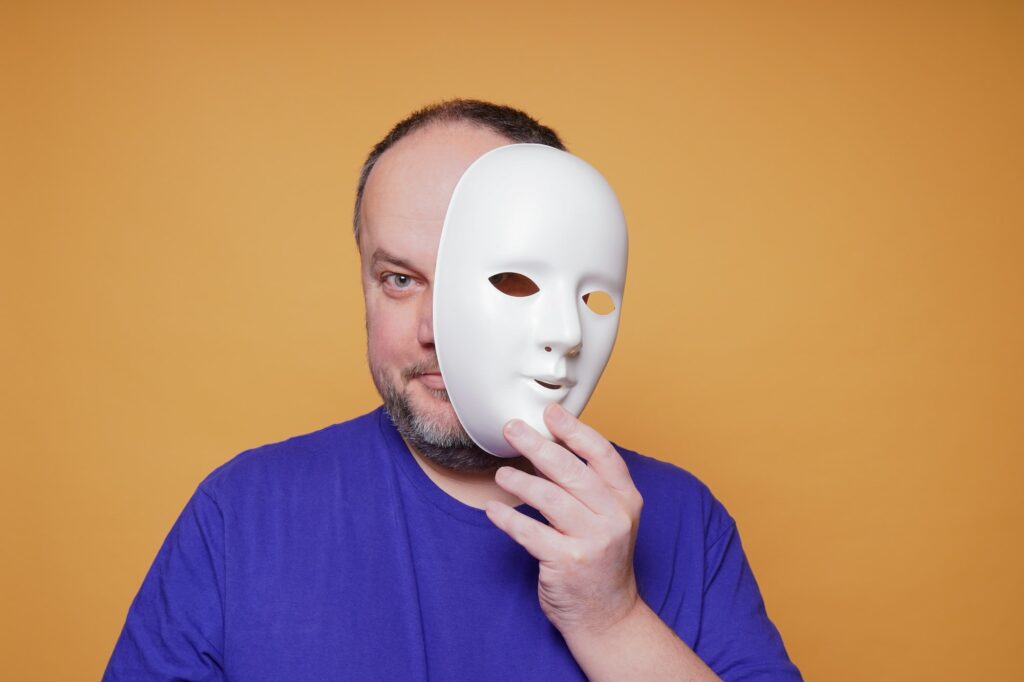 adult man taking off mask revealing face and identity