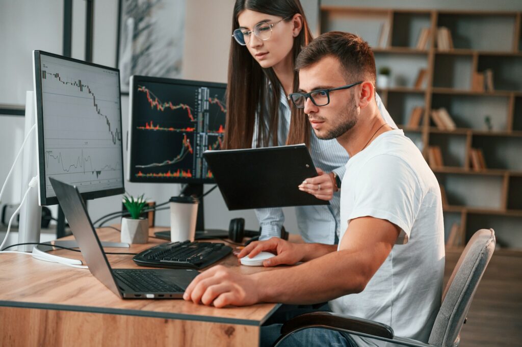 Analyzing information from computer screens. Two stock brokers is working together in the office