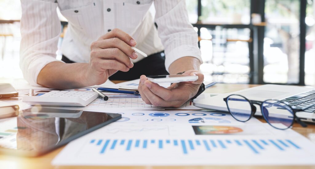 Businessman expert using smartphone analyze business report graph and finance chart at office.