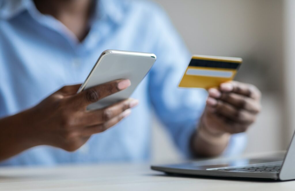 Money Transfers. Unrecognizable Black Businesswoman Using Smartphone And Credit Card For Payments