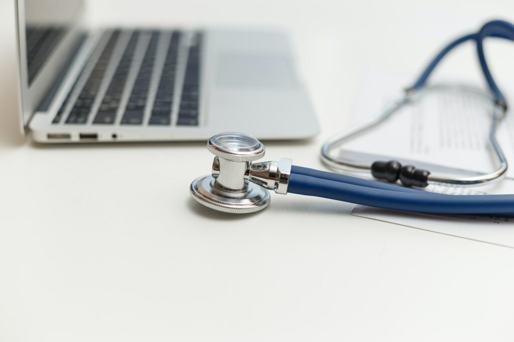 Stethoscope and laptop on doctor working desk, business and health care concept